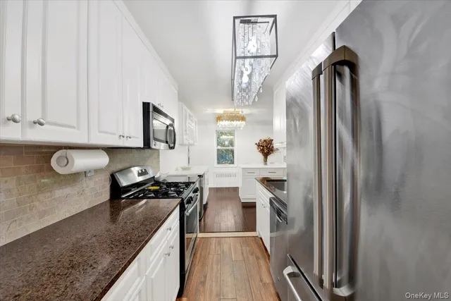 a kitchen with stainless steel appliances granite countertop a refrigerator a stove and a sink with wooden floor
