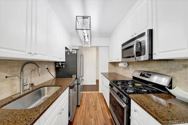a kitchen with granite countertop a sink stainless steel appliances and cabinets