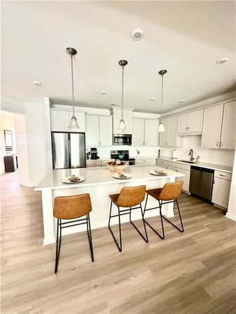 a kitchen with stainless steel appliances kitchen island granite countertop a table chairs stove and white cabinets