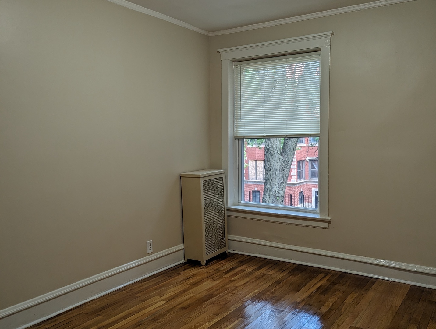 6730 South Ridgeland Avenue, Unit 2 Chicago, IL 60649 - Photo 4 of 12 a view of an empty room with wooden floor and a window