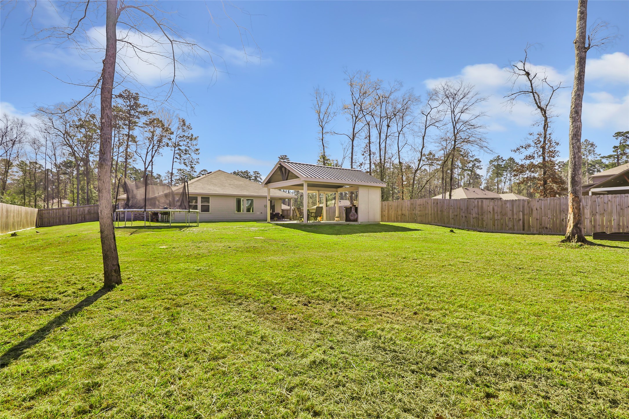 811 Republic Road New Caney, TX 77357 - Photo 11 of 37 Expansive backyard with lush grass, a covered patio, and a fenced perimeter, ideal for outdoor activities and relaxation. Surrounded by trees, providing privacy and a natural setting.