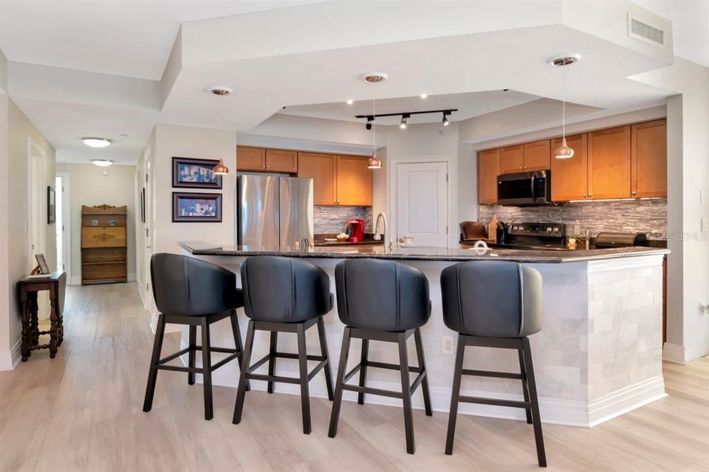 1350 Gulf Boulevard, Unit 301 Clearwater Beach, FL 33767 - Photo 13 of 75 a kitchen with stainless steel appliances granite countertop a table chairs refrigerator a sink dishwasher and a microwave