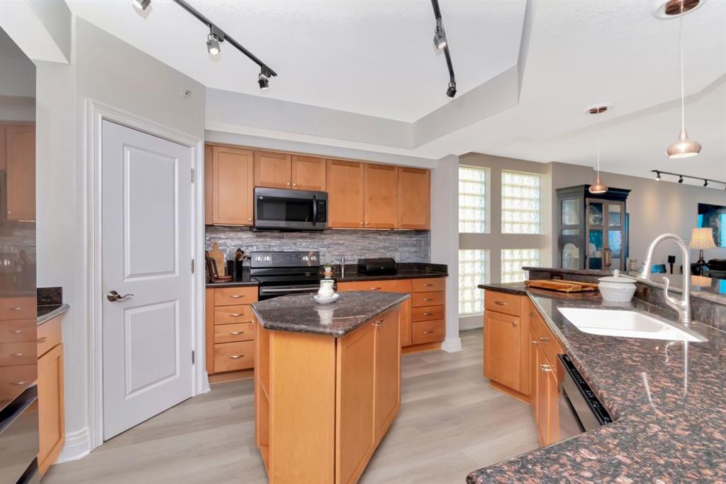 1350 Gulf Boulevard, Unit 301 Clearwater Beach, FL 33767 - Photo 16 of 75 a kitchen with stainless steel appliances granite countertop a stove top oven a sink dishwasher a refrigerator and a dining table with wooden floor