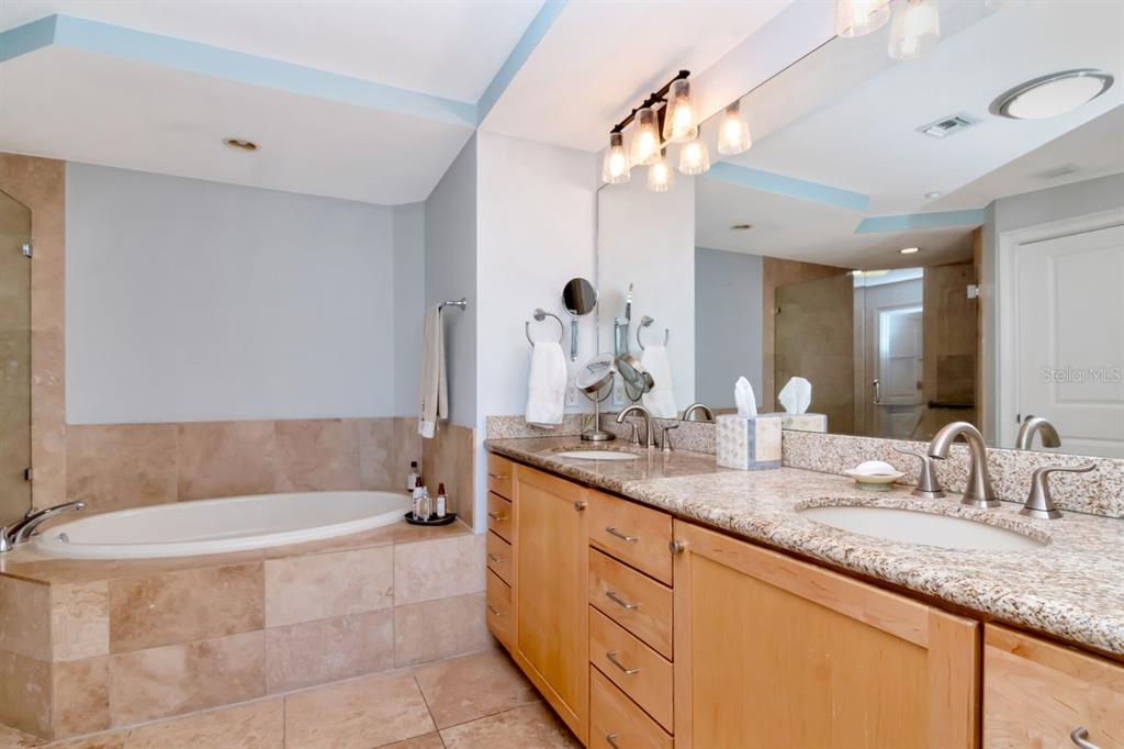 1350 Gulf Boulevard, Unit 301 Clearwater Beach, FL 33767 - Photo 22 of 75 a bathroom with a granite countertop bathtub sink and mirror