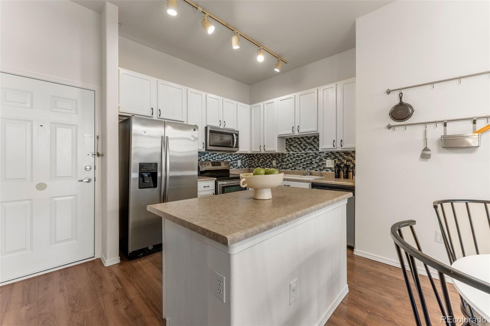 8420 Canyon Rim Trail, Unit 305 Parker, CO 80134 - Photo 37 of 44 a kitchen with stainless steel appliances granite countertop a refrigerator a stove and a sink with wooden floors
