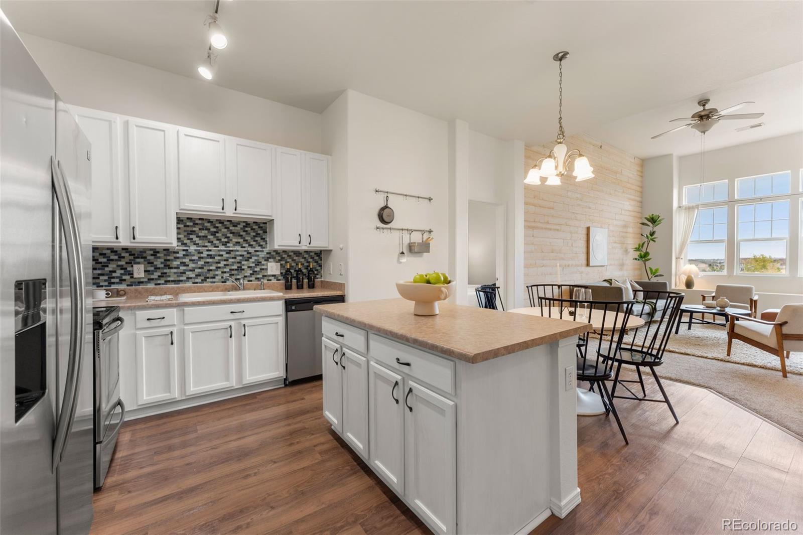 8420 Canyon Rim Trail, Unit 305 Parker, CO 80134 - Photo 8 of 44 a kitchen with white cabinets and chairs