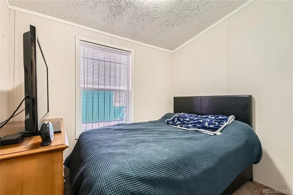a bedroom with a bed and a flat tv screen on a dresser