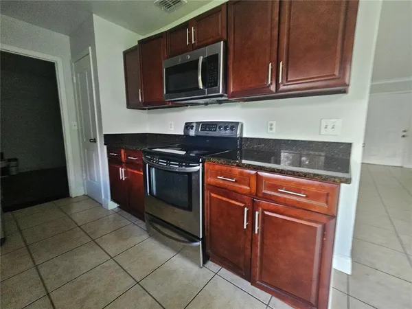 a kitchen with granite countertop a stove top oven microwave and cabinets