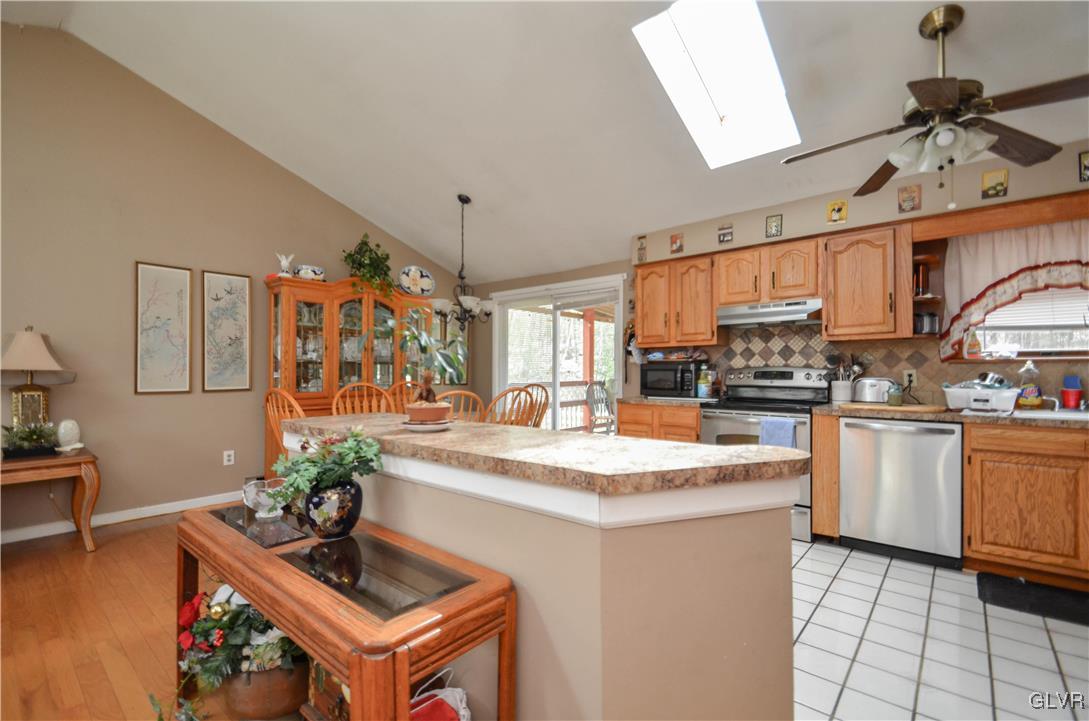 253 Sundance Road Effort, PA 18330 - Photo 8 of 25 a kitchen with stainless steel appliances kitchen island granite countertop a sink dishwasher a stove a dining table and chairs with wooden floor