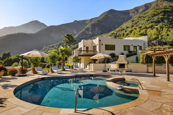 a view of a house with pool and chairs