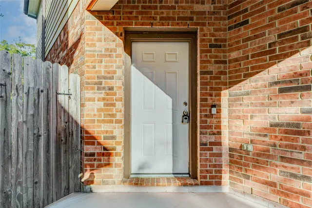 a view of wooden door with a brick wall