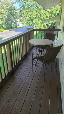 a balcony with wooden floor table and chairs
