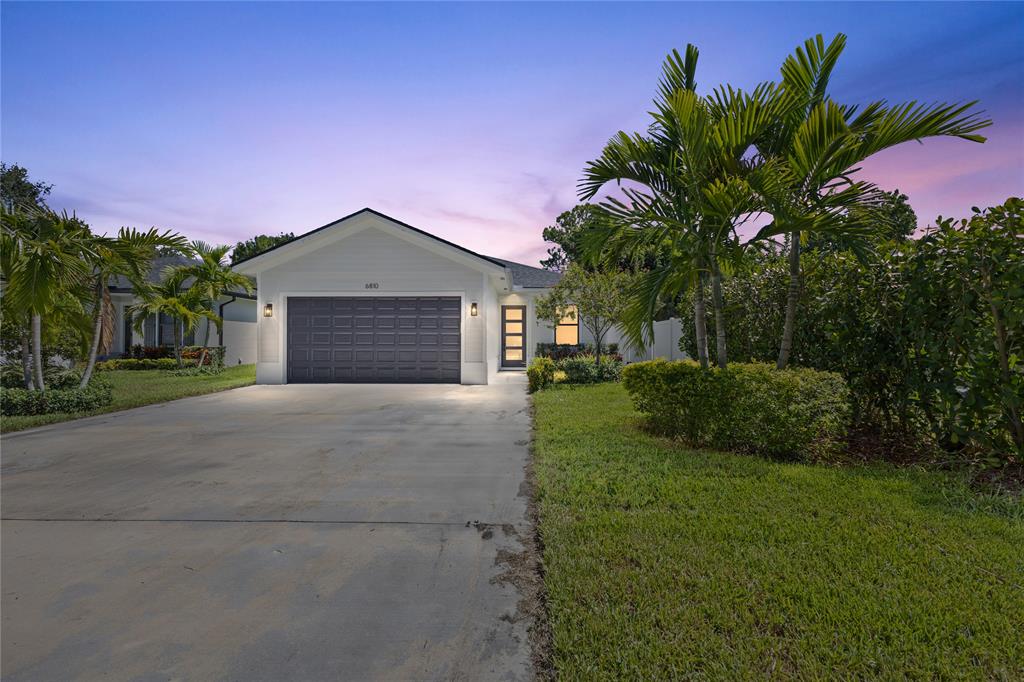 6810 Church Street Jupiter, FL 33458 - Photo 2 of 39 a front view of a house with a yard and garage