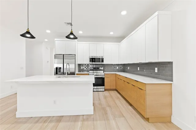 a kitchen with stainless steel appliances granite countertop a sink a stove and a refrigerator