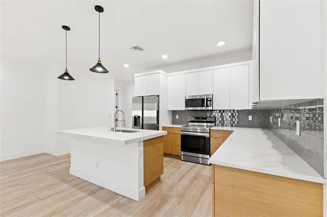 a kitchen with stainless steel appliances granite countertop a sink a stove and a refrigerator