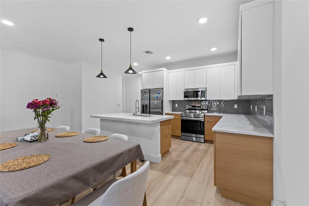 6810 Church Street Jupiter, FL 33458 - Photo 10 of 39 a kitchen with kitchen island a stove a sink a refrigerator and a dining table with wooden floor