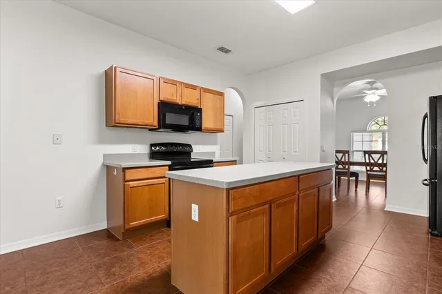 a kitchen with stainless steel appliances granite countertop a stove top oven a sink a dining table and chairs with wooden floor