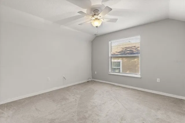 an empty room with windows and ceiling fan