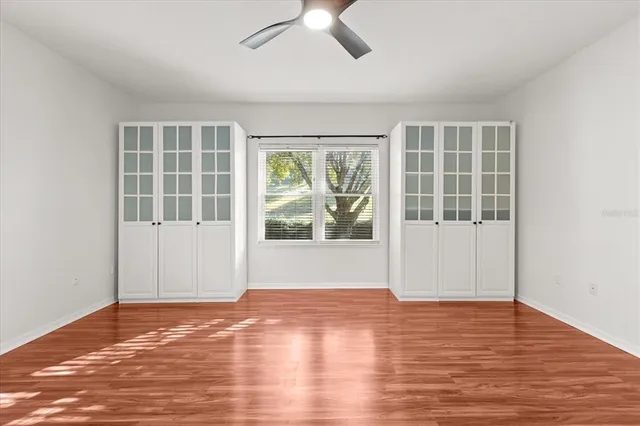 an empty room with wooden floor and windows