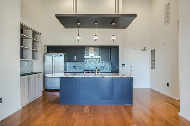 a large kitchen with stainless steel appliances a large counter top and wooden floors