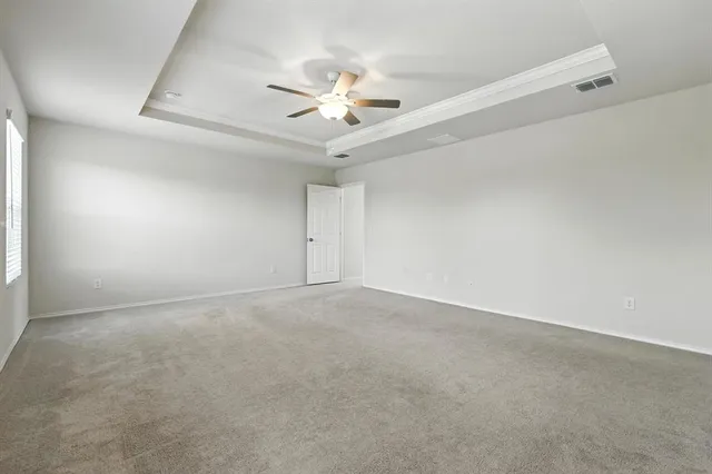 an empty room with chandelier fan and windows