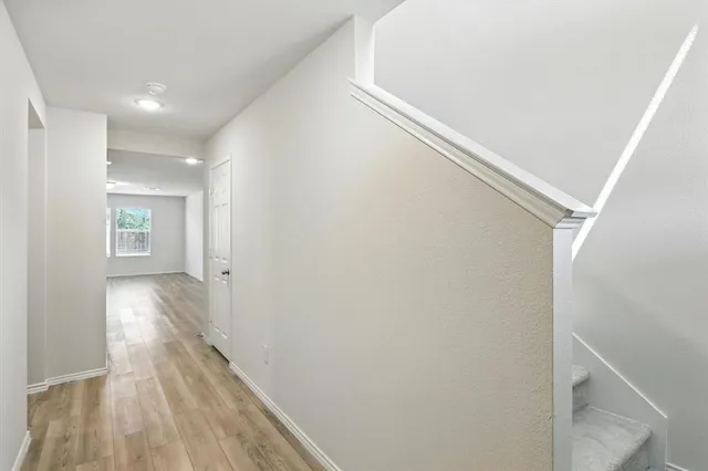 a view of hallway with window and wooden floor