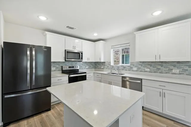 a kitchen with stainless steel appliances granite countertop a refrigerator a sink dishwasher a stove top oven a refrigerator with island and chairs