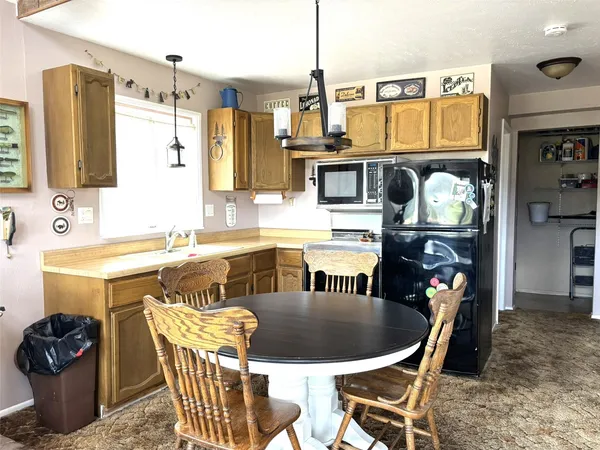 a kitchen with stainless steel appliances kitchen island granite countertop a table chairs and a refrigerator