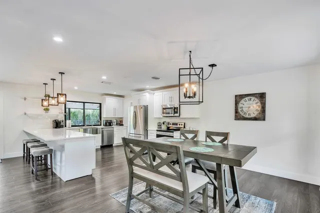 a kitchen with stainless steel appliances kitchen island a table chairs refrigerator and stove