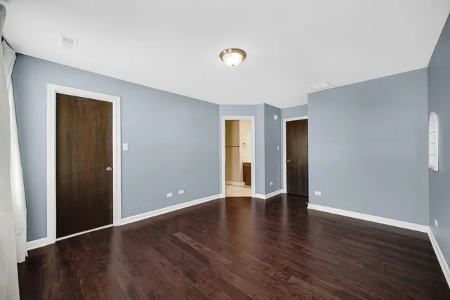 a view of an empty room with wooden floor and closet