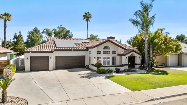 a front view of a house with yard garage and tree
