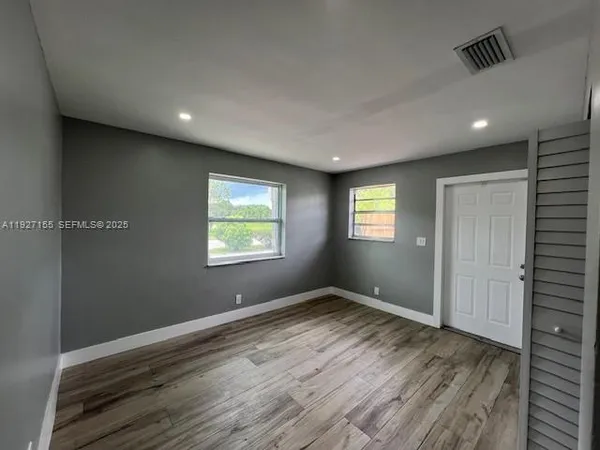 an empty room with wooden floor and windows