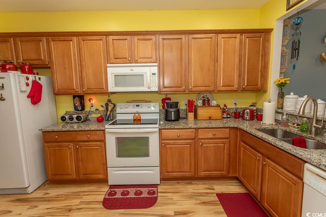 328 Kiskadee Loop, Unit E Conway, SC 29526 - Photo 9 of 37 Kitchen with white appliances, brown cabinetry, and light stone counters