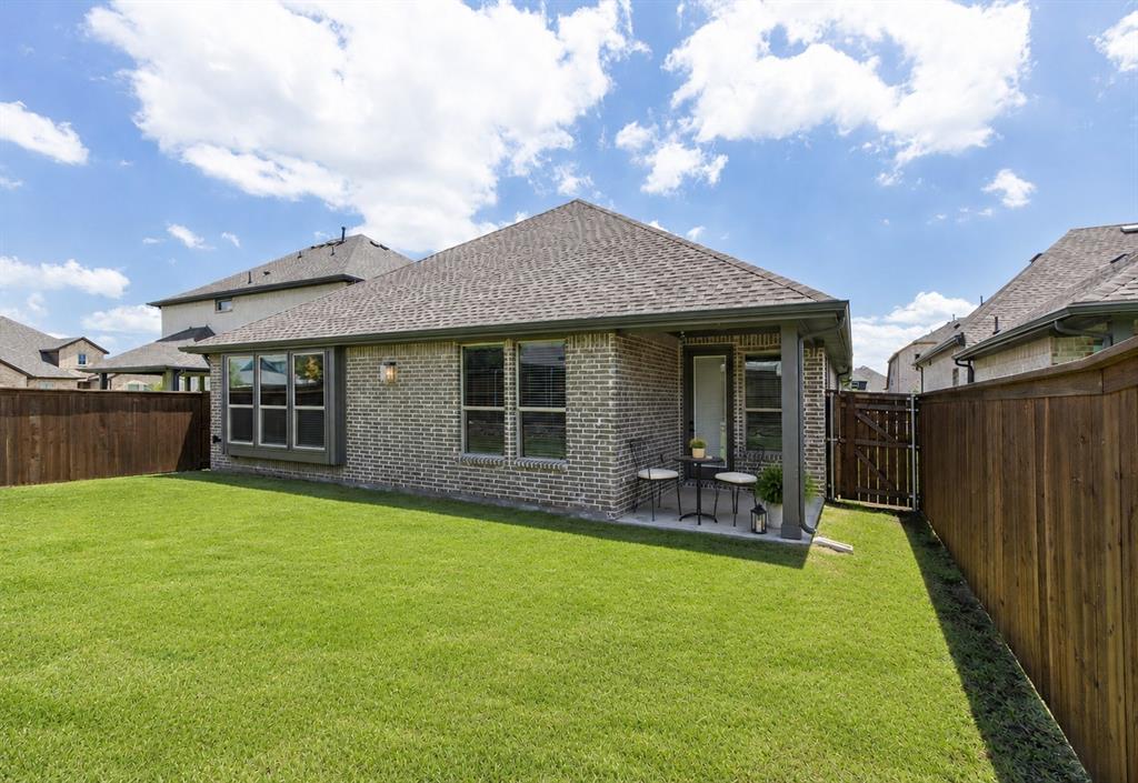 3311 Willena Road Melissa, TX 75454 - Photo 23 of 40 Expansive backyard featuring a manicured lawn, full privacy fencing, a covered patio, and a brick exterior with multiple windows