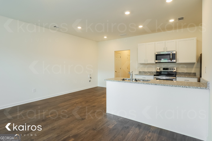 115 Dudley Way Southwest Cartersville, GA 30120 - Photo 6 of 16 a kitchen with granite countertop a stove a sink and a refrigerator