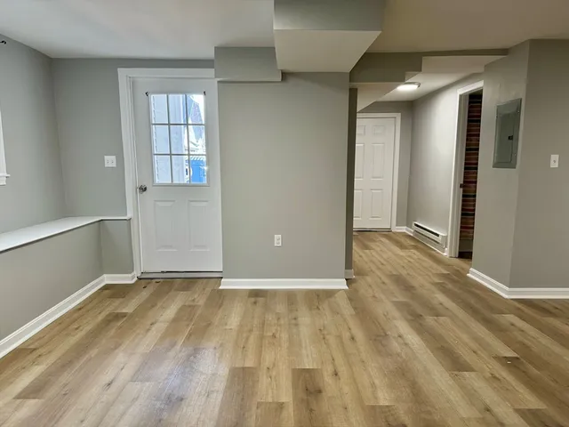 a view of an empty room with window and wooden floor
