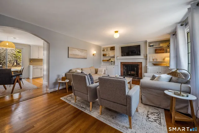 a living room with furniture a fireplace a flat screen tv and windows