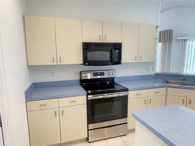 a kitchen with granite countertop a stove top oven microwave and cabinets