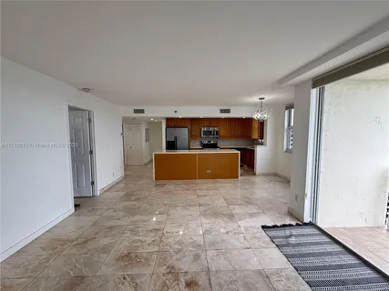 a view of kitchen and empty room with wooden floor