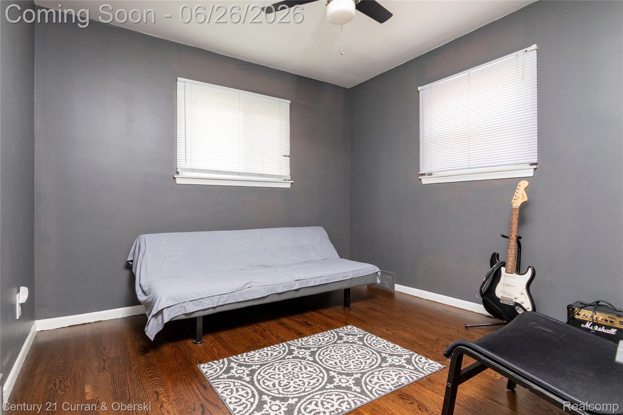 3220 Alice Street Dearborn, MI 48124 - Photo 16 of 39 Room featuring dark wood-finish flooring, two windows with white blinds, a ceiling fan, and dark gray walls