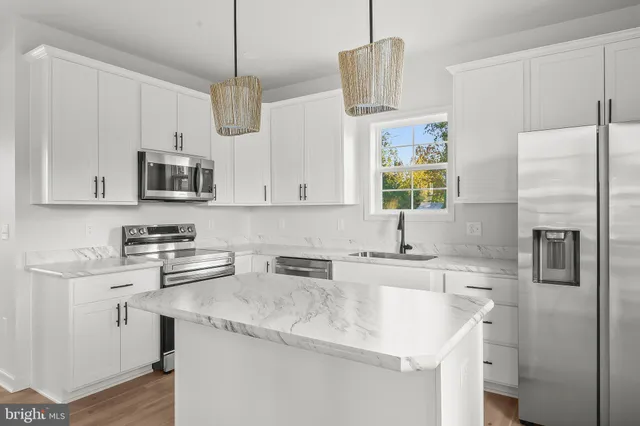 a kitchen with stainless steel appliances granite countertop a sink a stove a refrigerator a center island and cabinets