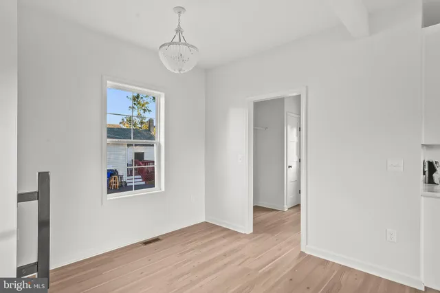 a view of an empty room with window and wooden floor