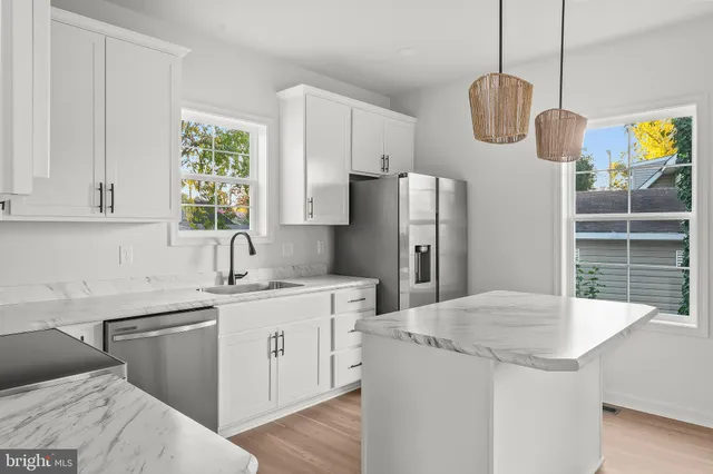 a kitchen with stainless steel appliances granite countertop a sink a stove a refrigerator a center island with wooden floor and cabinets