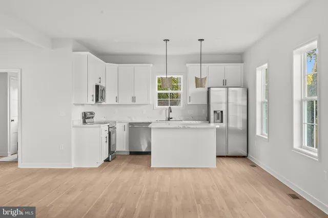 a kitchen with a refrigerator a stove top oven and white cabinets