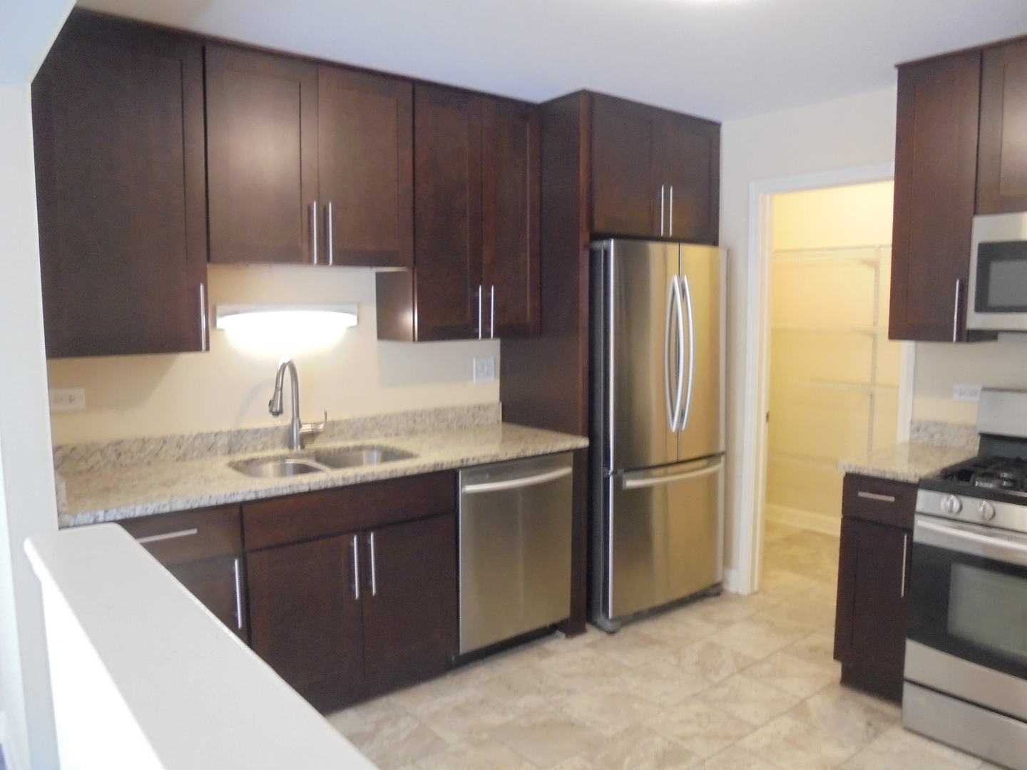 1534 Springview Court, Unit B2 Wheeling, IL 60090 - Photo 15 of 29 a kitchen with kitchen island granite countertop wooden cabinets and stainless steel appliances
