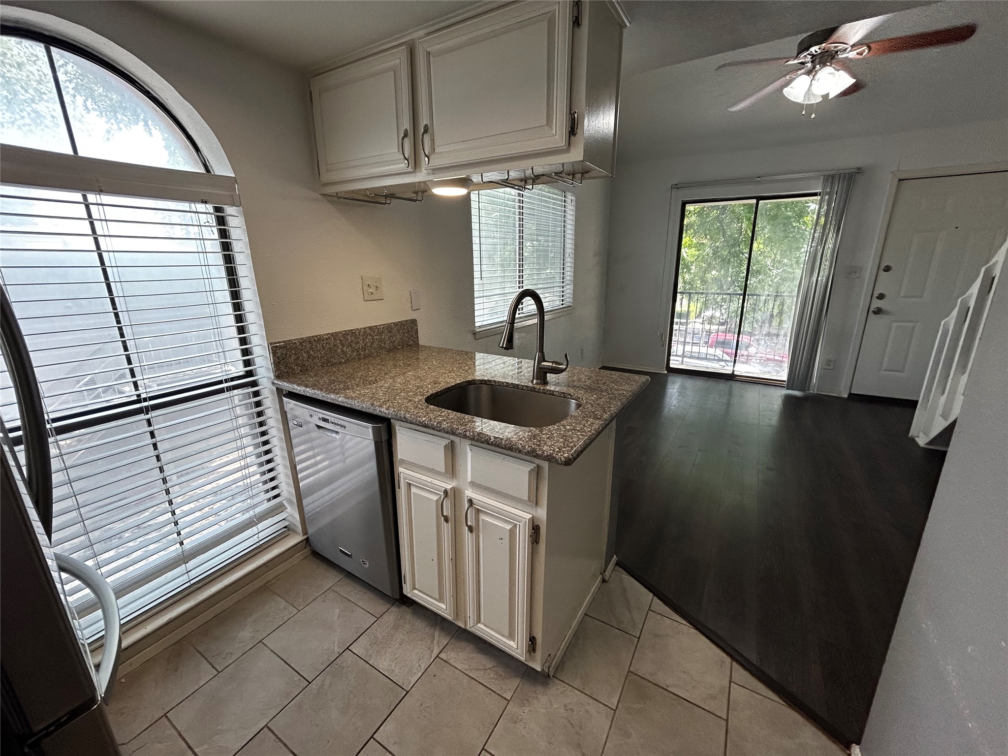 708 Graham Place, Unit 208 Austin, TX 78705 - Photo 1 of 9 Kitchen featuring dark stone counters, dishwasher, freestanding refrigerator, white cabinets, and ceiling fan