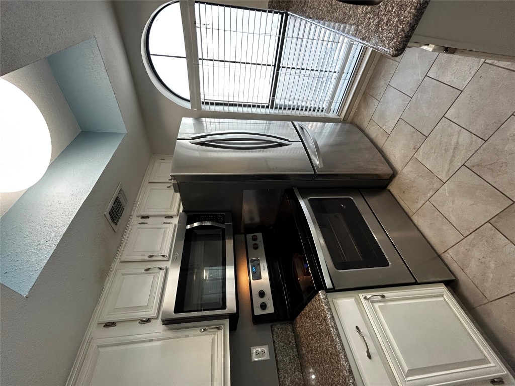 708 Graham Place, Unit 208 Austin, TX 78705 - Photo 2 of 9 a kitchen with granite countertop a stove a microwave a refrigerator and cabinets