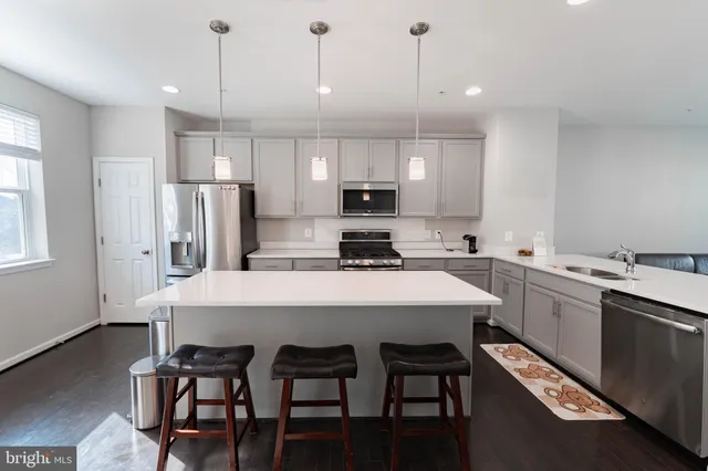 a kitchen with stainless steel appliances a table chairs refrigerator and microwave