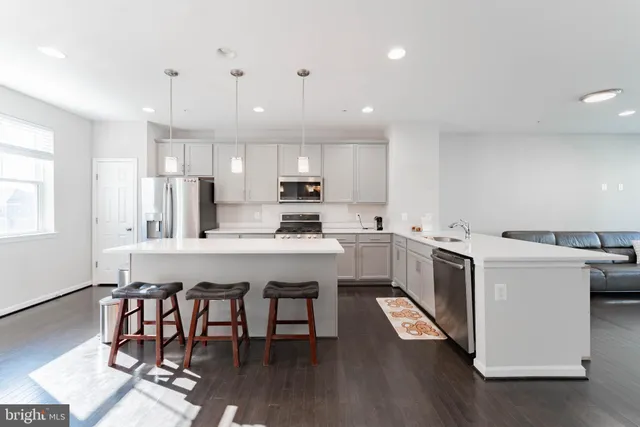 a kitchen that has a lot of cabinets in it with wooden floor and appliances