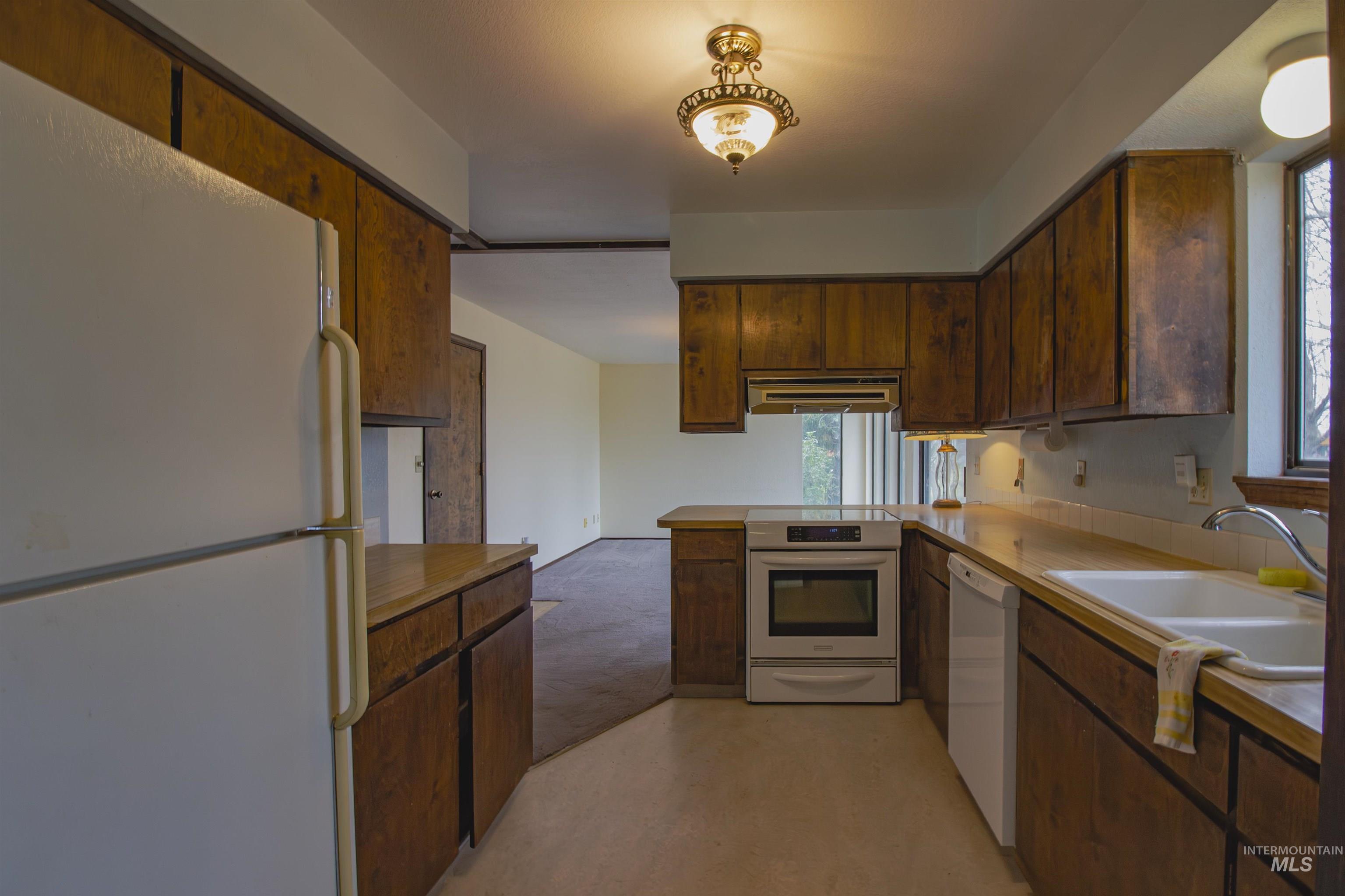 2465 Center Avenue Payette, ID 83661 - Photo 11 of 39 Kitchen with white appliances, a peninsula with a breakfast bar, ventilation hood, and light countertops